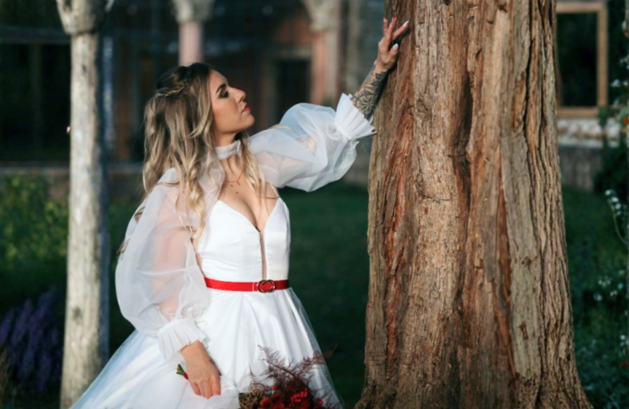 Jeune mariée portant des accessoires en cuir artisanaux près d'un cèdre.