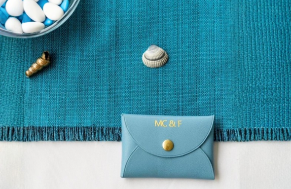 Petite pochette en cuir bleu personnalisée posée sur une nappe bleue.